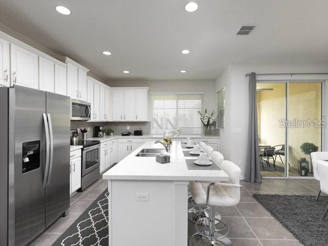 kitchen featuring sink, a breakfast bar area, white cabinetry, an island with sink, and stainless steel appliances