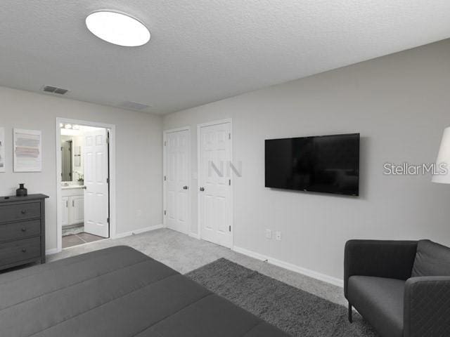 carpeted bedroom with a textured ceiling, multiple closets, and ensuite bathroom