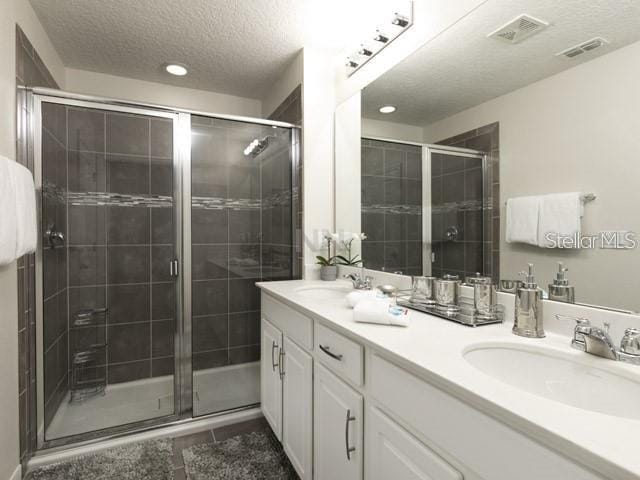 bathroom with tile patterned flooring, vanity, a textured ceiling, and an enclosed shower