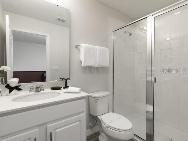 bathroom featuring vanity, toilet, tile patterned flooring, and a shower with door