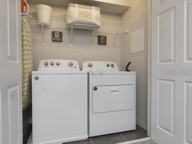 washroom featuring washing machine and clothes dryer and dark tile patterned flooring