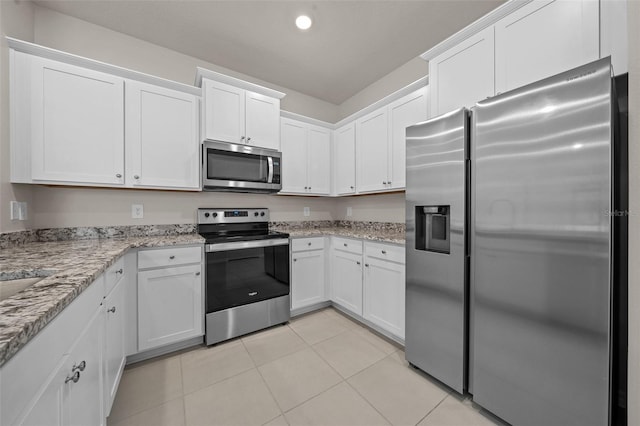 kitchen featuring stainless steel appliances, light tile patterned floors, white cabinets, and light stone counters