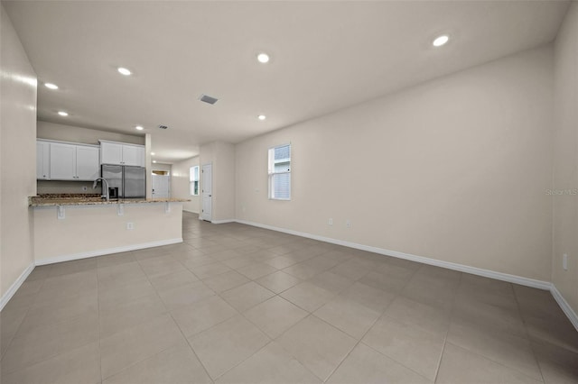 unfurnished living room with light tile patterned flooring and sink