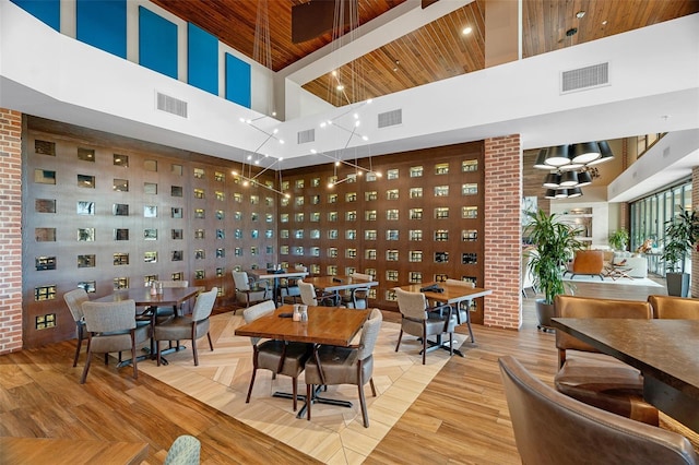 dining space featuring a towering ceiling, light hardwood / wood-style floors, and wooden ceiling