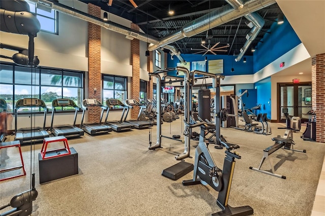 gym with a high ceiling and brick wall