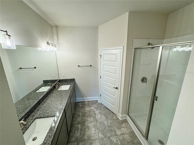 bathroom featuring vanity, a shower with shower door, and a textured ceiling