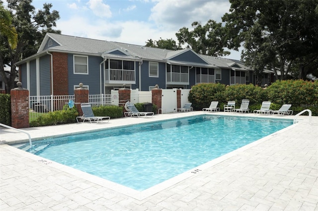 community pool with fence and a patio