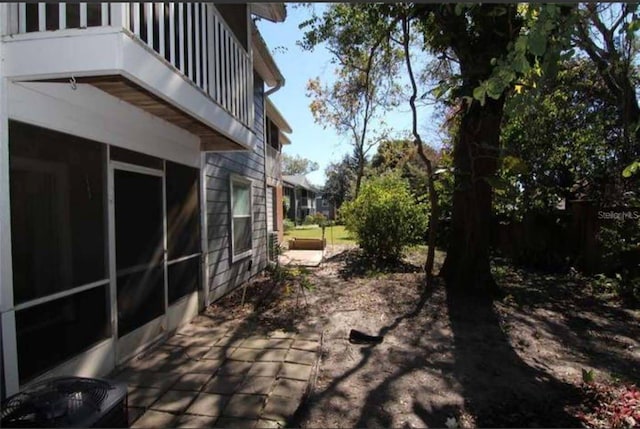 view of patio featuring a sunroom and a balcony