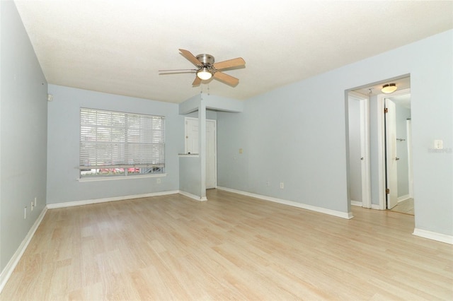 spare room with light wood finished floors, a ceiling fan, and baseboards