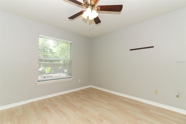 spare room with baseboards, ceiling fan, a textured ceiling, and light wood finished floors