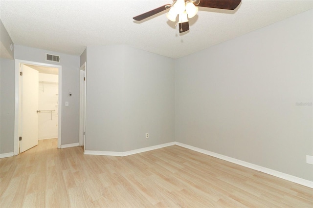 unfurnished room with baseboards, visible vents, a ceiling fan, a textured ceiling, and light wood-style floors