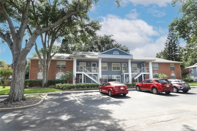 view of property featuring uncovered parking and stairway