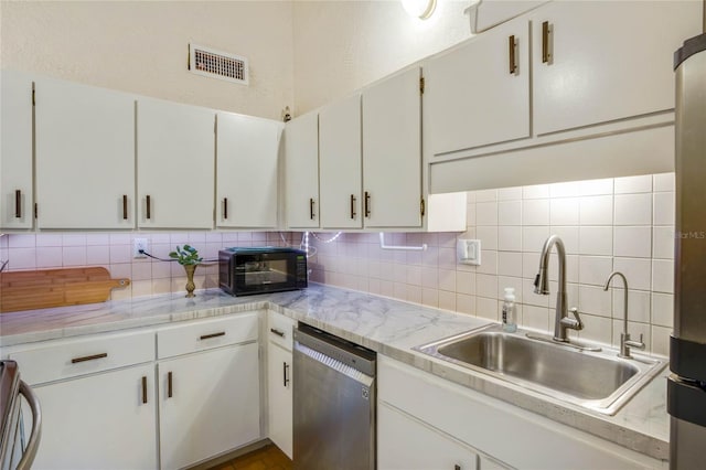 kitchen featuring decorative backsplash, stainless steel appliances, white cabinetry, and sink