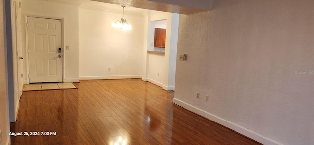 spare room with crown molding, a chandelier, and light hardwood / wood-style floors