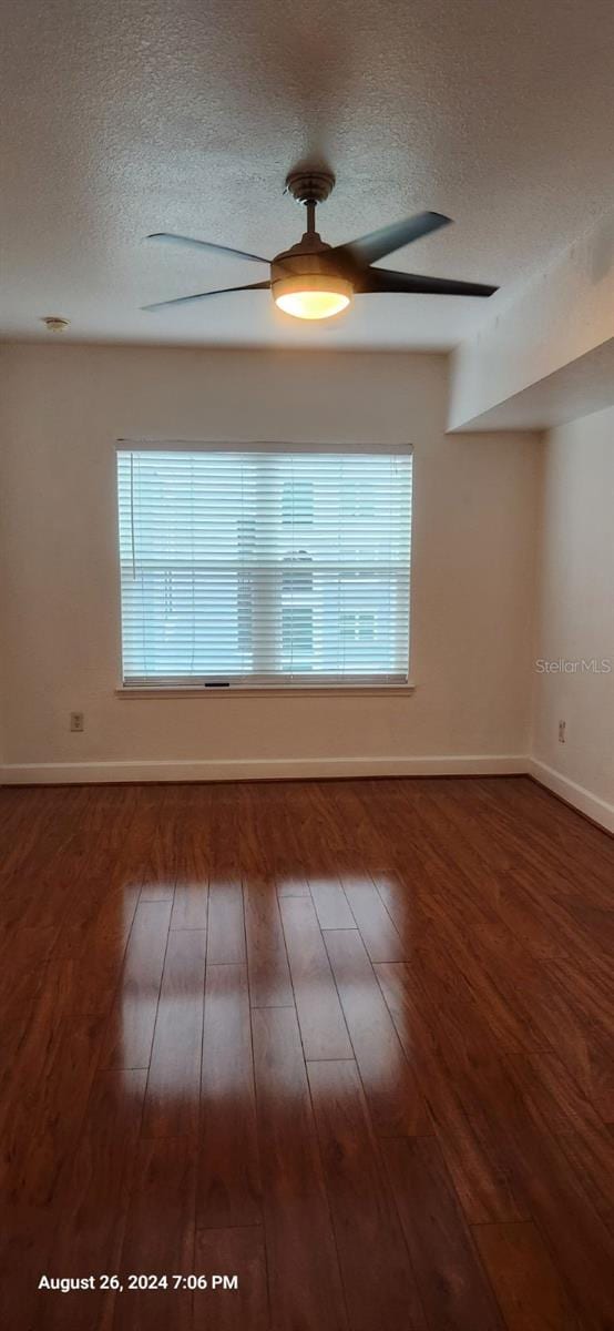 spare room with dark hardwood / wood-style floors and a textured ceiling