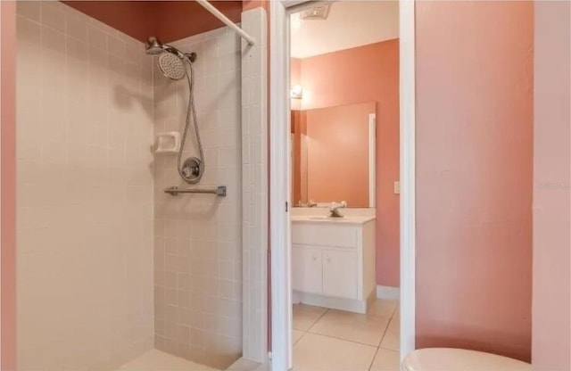 bathroom featuring vanity, tile patterned floors, toilet, and a tile shower