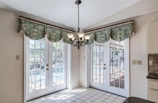 entryway featuring french doors, light tile patterned floors, and a notable chandelier