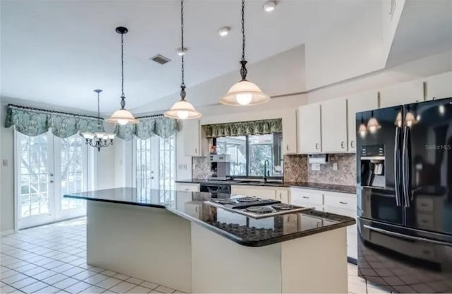 kitchen featuring tasteful backsplash, black appliances, hanging light fixtures, a kitchen island, and white cabinets