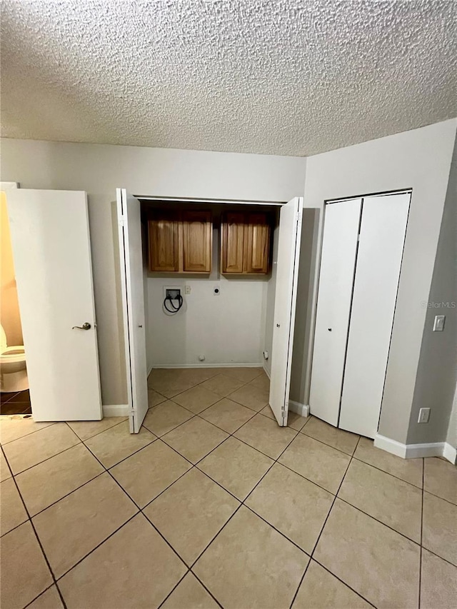 clothes washing area featuring washer hookup, a textured ceiling, cabinets, hookup for an electric dryer, and light tile patterned flooring