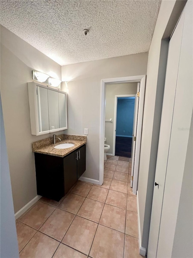 bathroom featuring a textured ceiling, vanity, tile patterned floors, and toilet