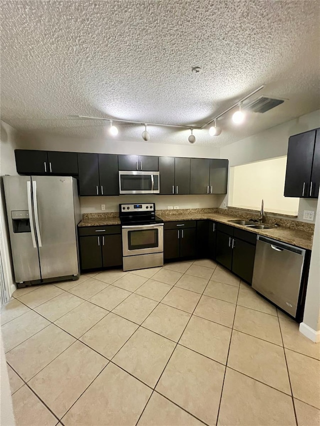 kitchen featuring appliances with stainless steel finishes, track lighting, sink, and light tile patterned floors