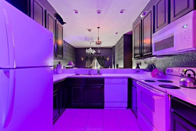 kitchen with white appliances, sink, hanging light fixtures, a notable chandelier, and kitchen peninsula