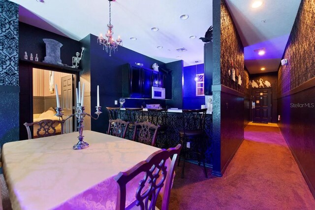 dining space with dark colored carpet and an inviting chandelier