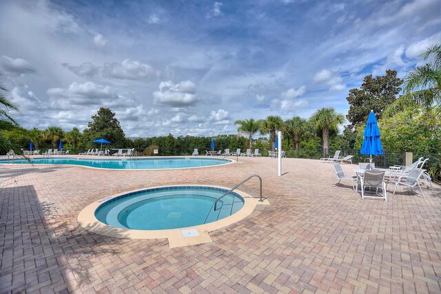 view of swimming pool with a hot tub and a patio area