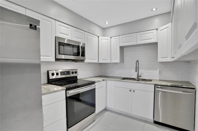 kitchen with white cabinetry, sink, light stone counters, and appliances with stainless steel finishes