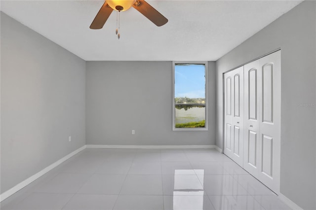 unfurnished bedroom with light tile patterned flooring, ceiling fan, and a closet