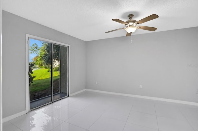 unfurnished room with ceiling fan, light tile patterned floors, and a textured ceiling