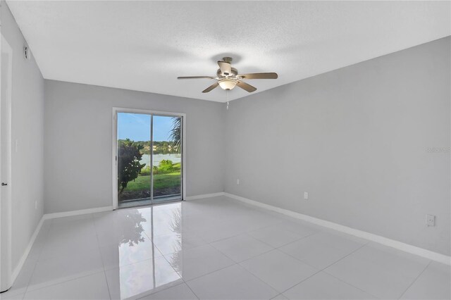 empty room with light tile patterned flooring, a textured ceiling, and ceiling fan