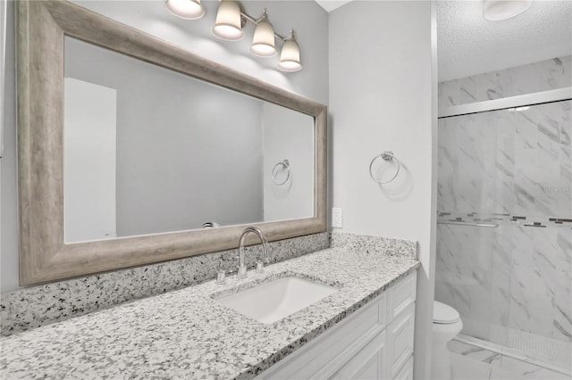 bathroom featuring toilet, vanity, a textured ceiling, and walk in shower