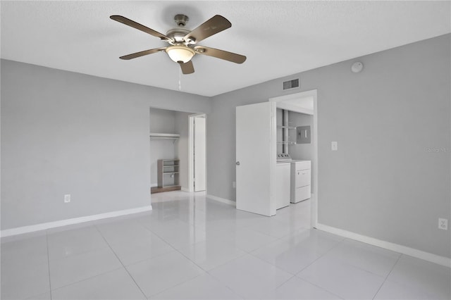 tiled empty room featuring ceiling fan, a textured ceiling, electric panel, and washing machine and clothes dryer