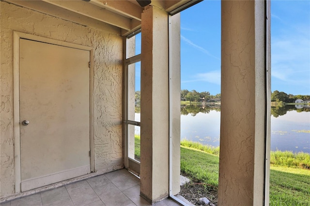 doorway with light tile patterned flooring, a water view, and plenty of natural light