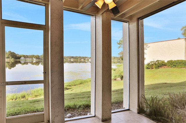 sunroom with plenty of natural light, a water view, and ceiling fan