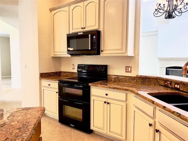 kitchen featuring range with two ovens, cream cabinets, and dark stone countertops