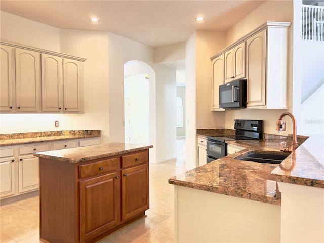 kitchen with sink, a center island, light tile patterned floors, stone countertops, and black appliances