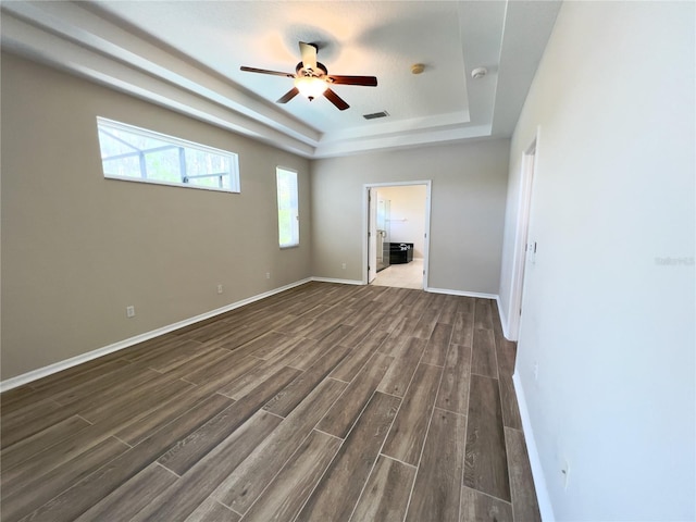 unfurnished room featuring ceiling fan, a tray ceiling, and dark hardwood / wood-style floors