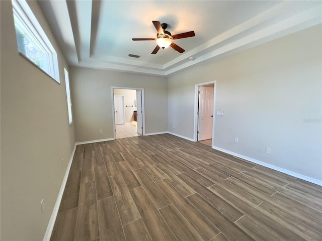 interior space featuring dark hardwood / wood-style flooring, a raised ceiling, ceiling fan, and ensuite bath