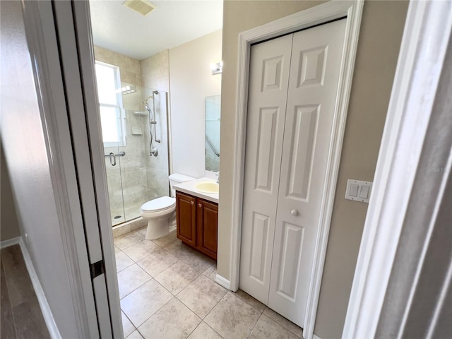 bathroom with toilet, a shower with door, tile patterned floors, and vanity