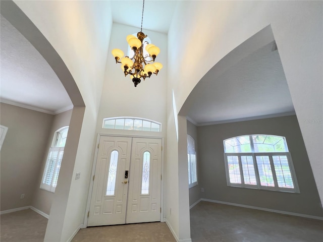 entryway with a towering ceiling, a chandelier, and ornamental molding