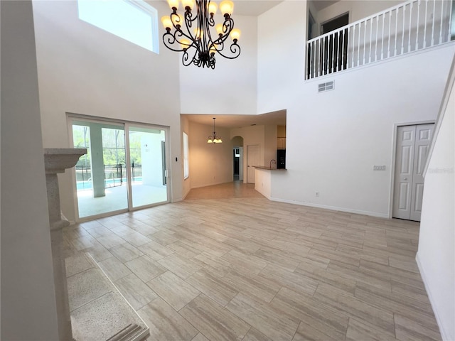 unfurnished living room featuring a high ceiling, sink, and a chandelier