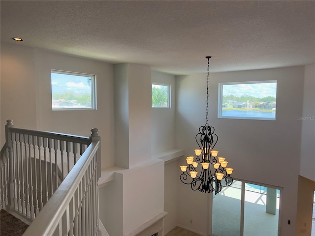 interior space featuring a textured ceiling, carpet floors, and a chandelier