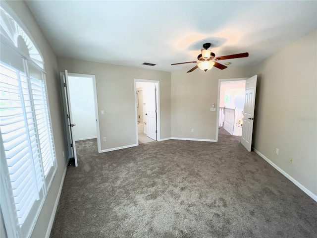 unfurnished bedroom featuring ceiling fan, connected bathroom, and dark carpet