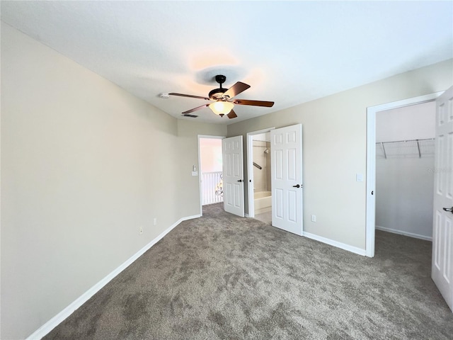 unfurnished bedroom featuring ceiling fan, a spacious closet, a closet, and carpet