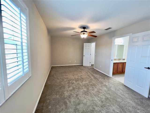 unfurnished bedroom featuring ceiling fan, ensuite bath, and carpet