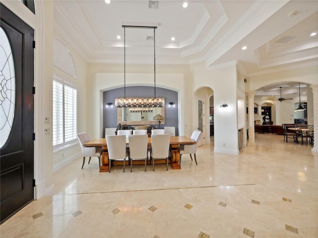 dining area featuring ceiling fan with notable chandelier, ornamental molding, a high ceiling, and a tray ceiling