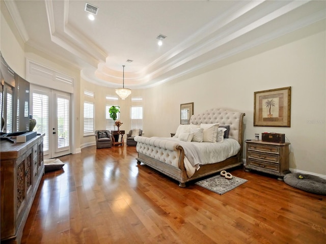 bedroom with access to exterior, wood-type flooring, multiple windows, and a tray ceiling