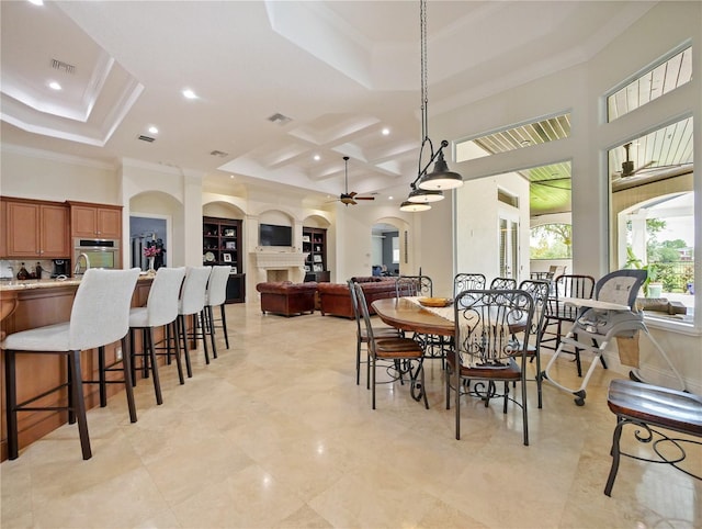 dining space featuring ceiling fan, built in features, crown molding, and a high ceiling